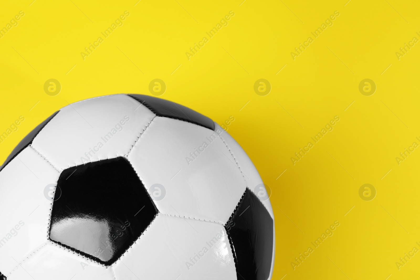 Photo of One soccer ball on yellow background, top view with space for text. Sports equipment