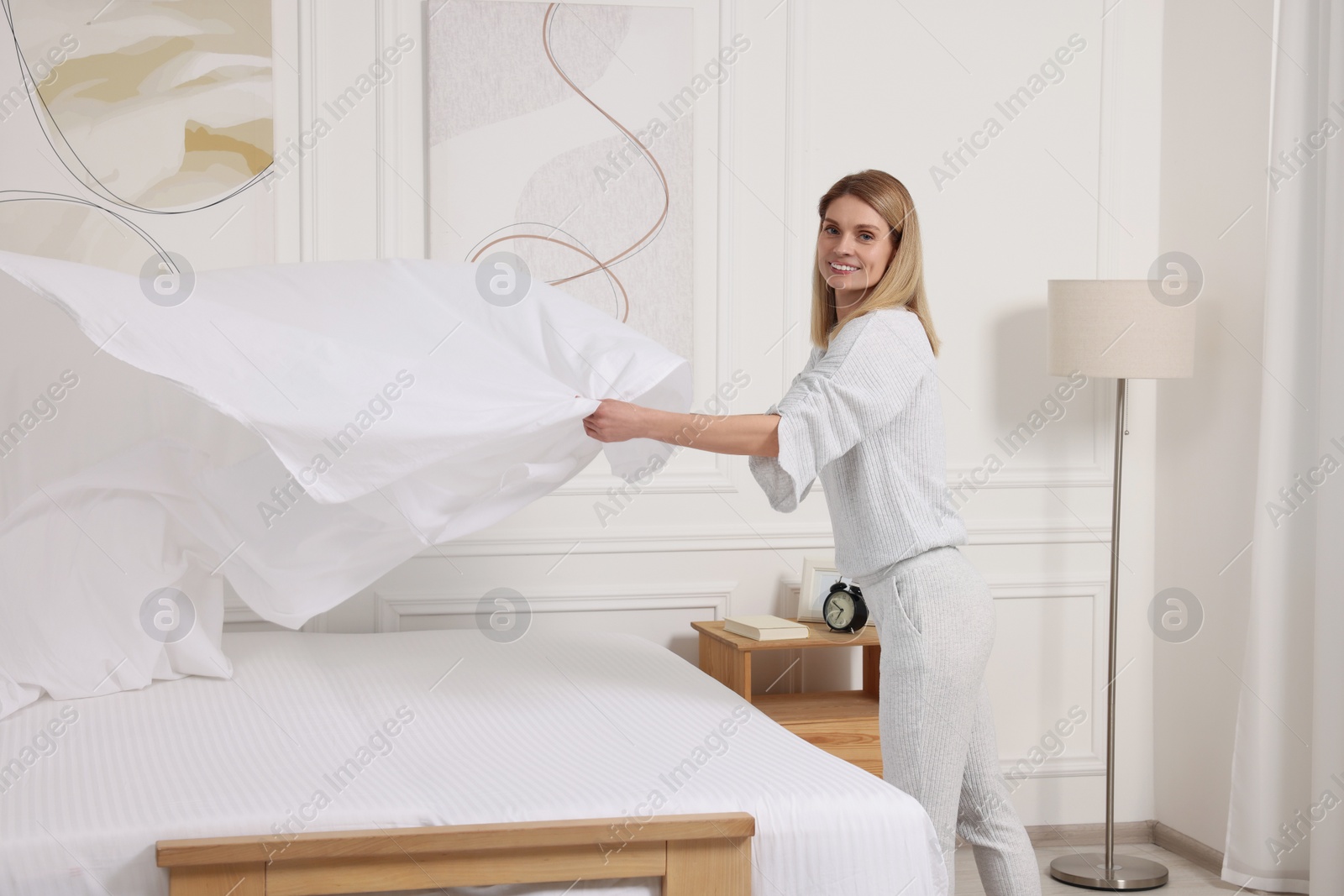 Photo of Woman changing bed linens at home. Space for text