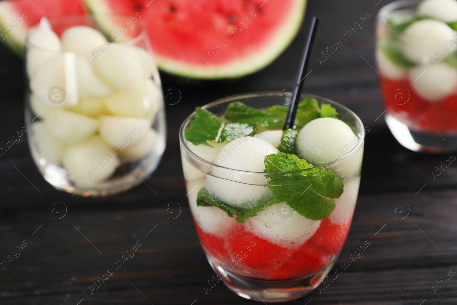 Photo of Glass with tasty melon and watermelon ball drink on dark table