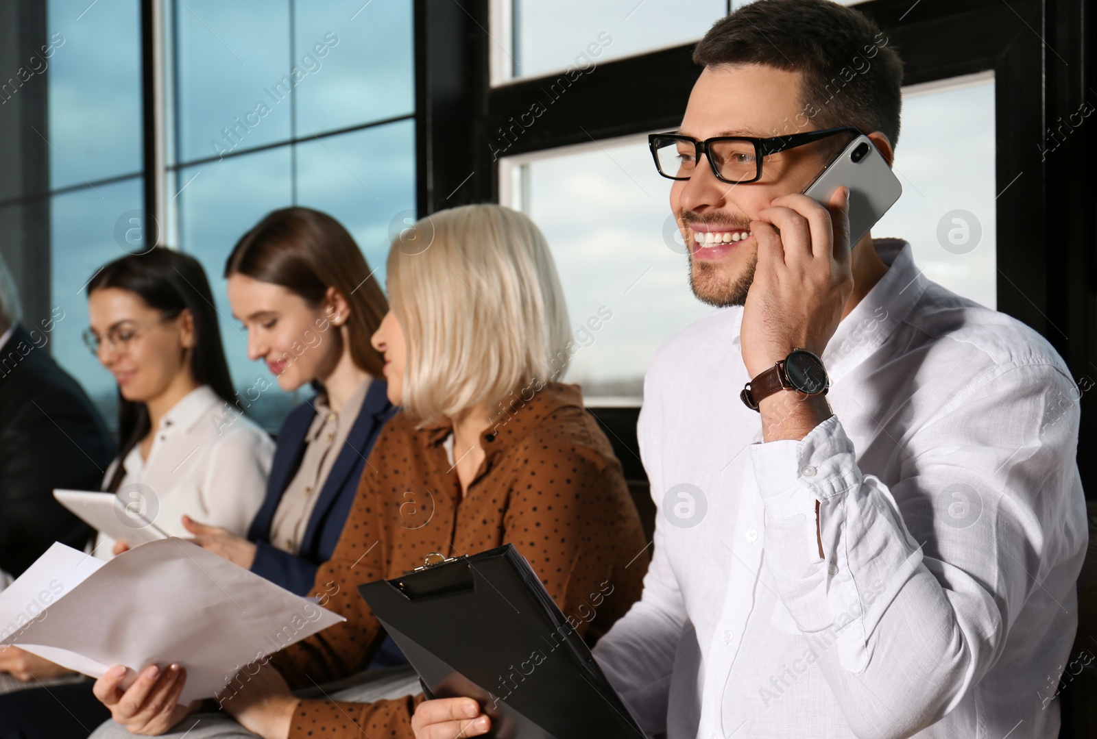 Photo of Man talking on phone while waiting for job interview in office hall