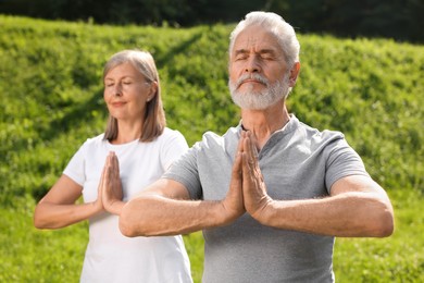 Senior couple practicing yoga outdoors, selective focus