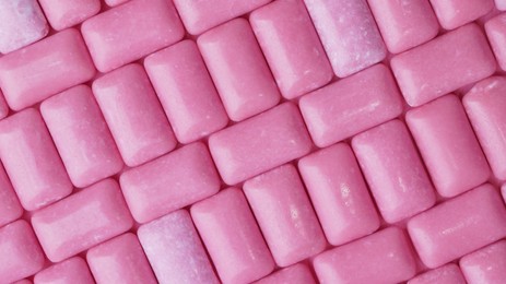 Photo of Many pink chewing gums as background, top view