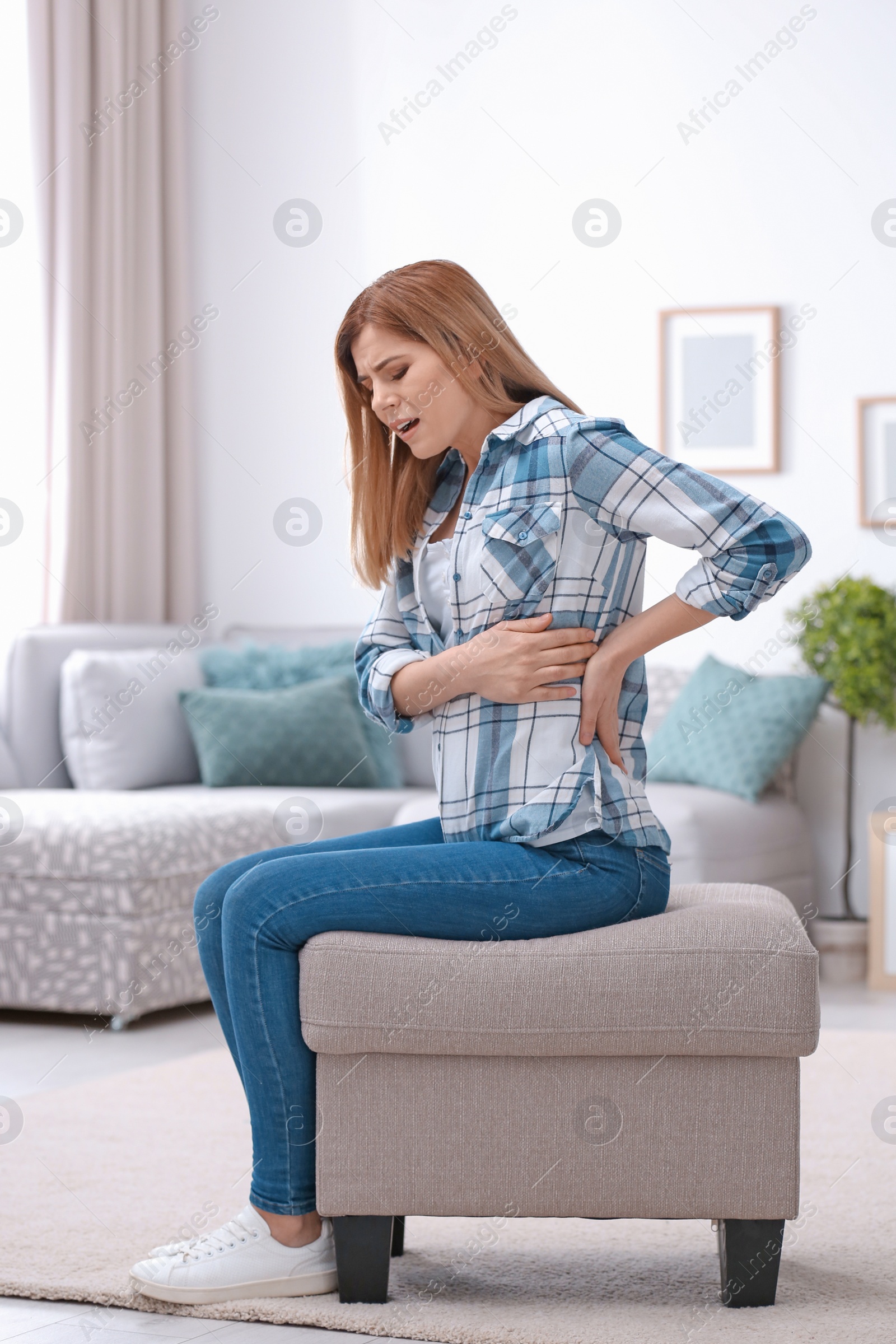 Photo of Young woman suffering from back pain at home