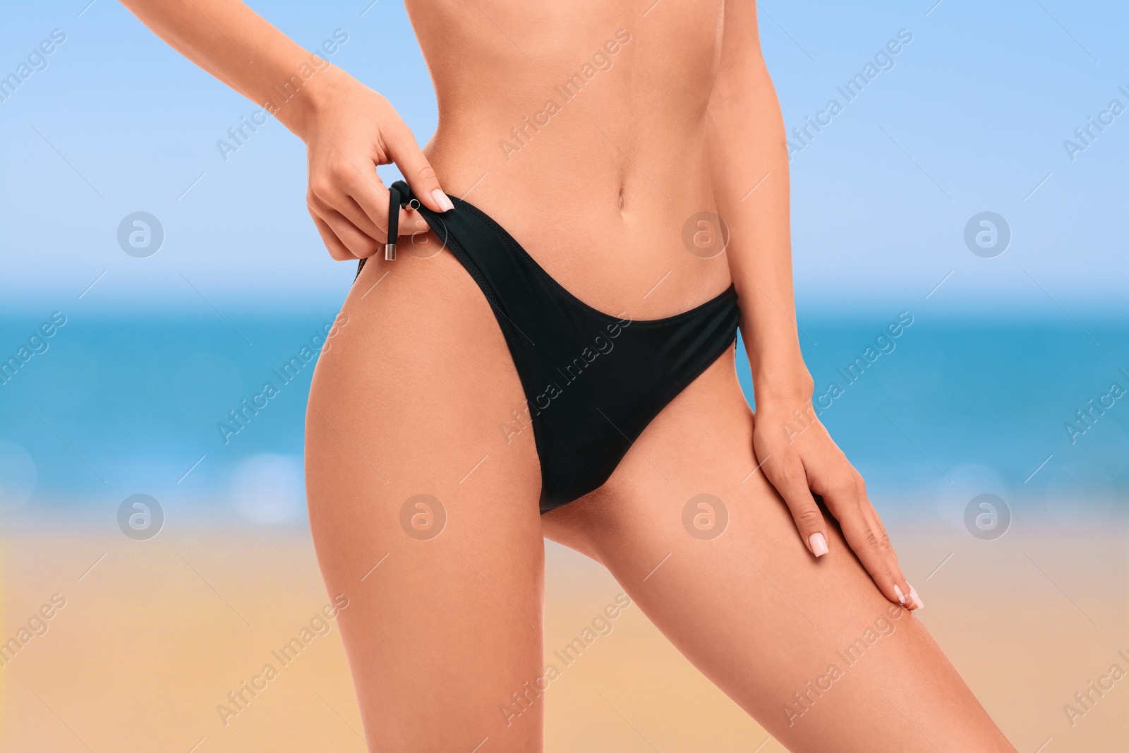 Image of Woman in stylish black bikini on sandy beach near sea, closeup