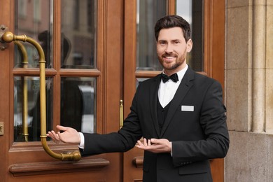 Photo of Butler in elegant suit near wooden hotel door