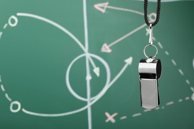 Photo of Referee whistle against green chalkboard with game scheme, closeup. Space for text