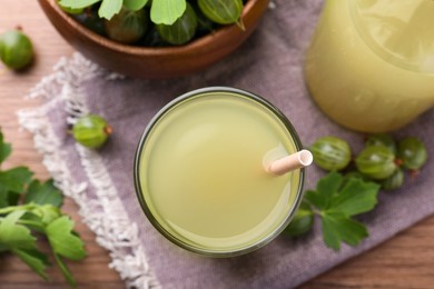 Photo of Tasty gooseberry juice in glass on table, flat lay