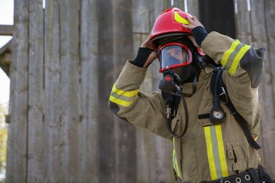 Photo of Firefighter in uniform wearing helmet and mask outdoors, space for text