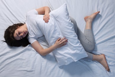 Photo of Young woman suffering from insomnia in bed, top view