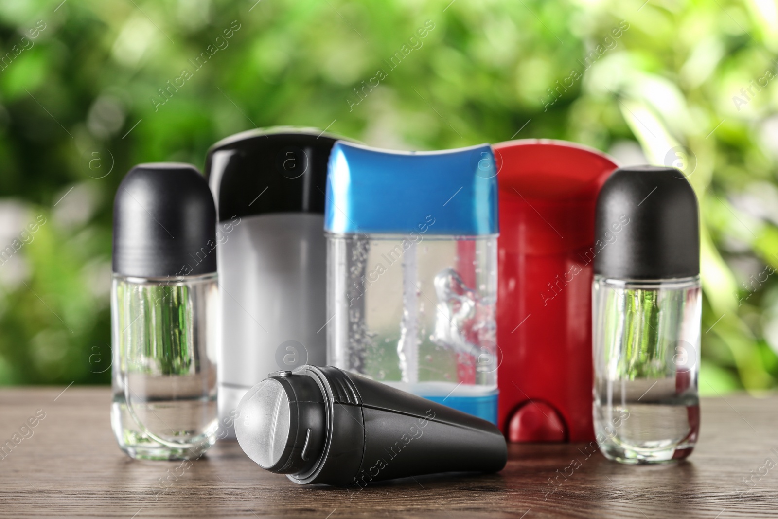 Photo of Different deodorants on wooden table against blurred background