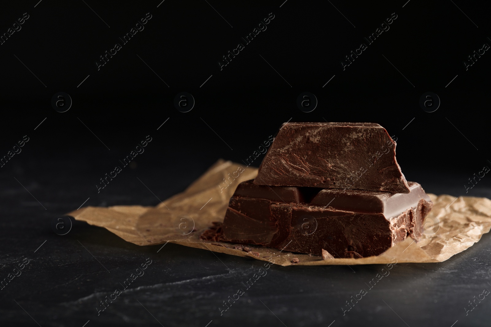 Photo of Pieces of dark chocolate on black table