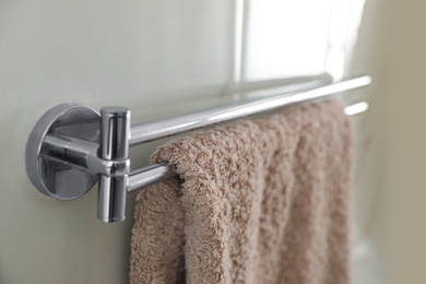 Holder with clean towel on light wall in bathroom, closeup