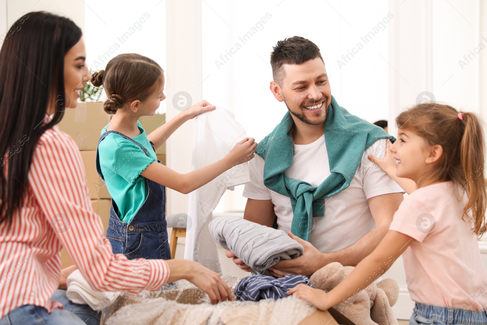 Photo of Happy family unpacking moving box in new house