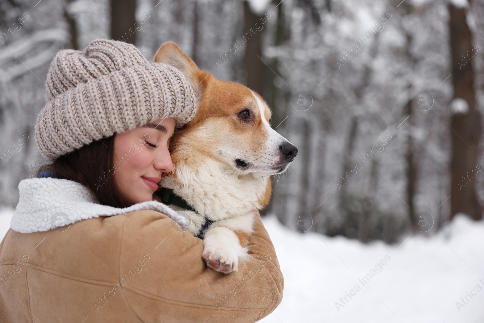 Photo of Woman with adorable Pembroke Welsh Corgi dog in snowy park, space for text