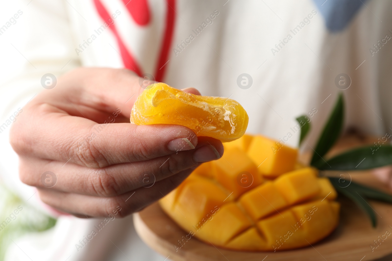 Photo of Woman holding delicious mango mochi, closeup. Japanese cuisine