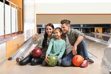 Photo of Happy family taking selfie in bowling club