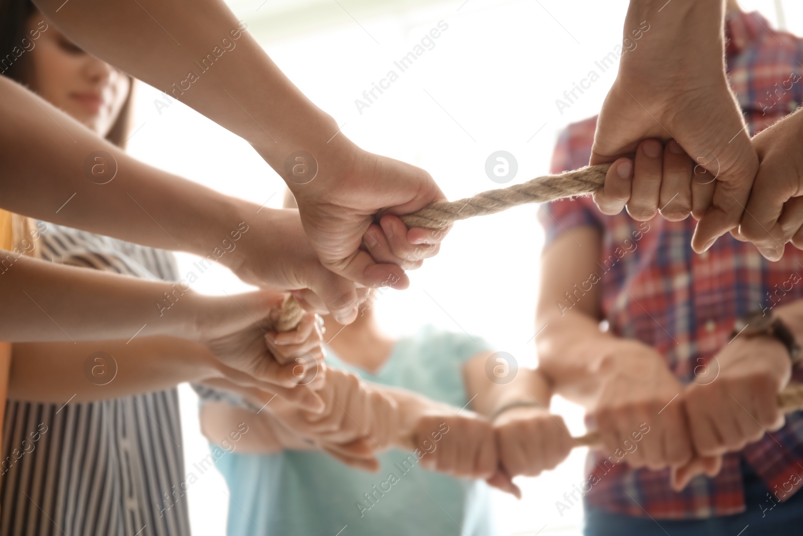 Photo of People holding rope together on light background, closeup of hands. Unity concept