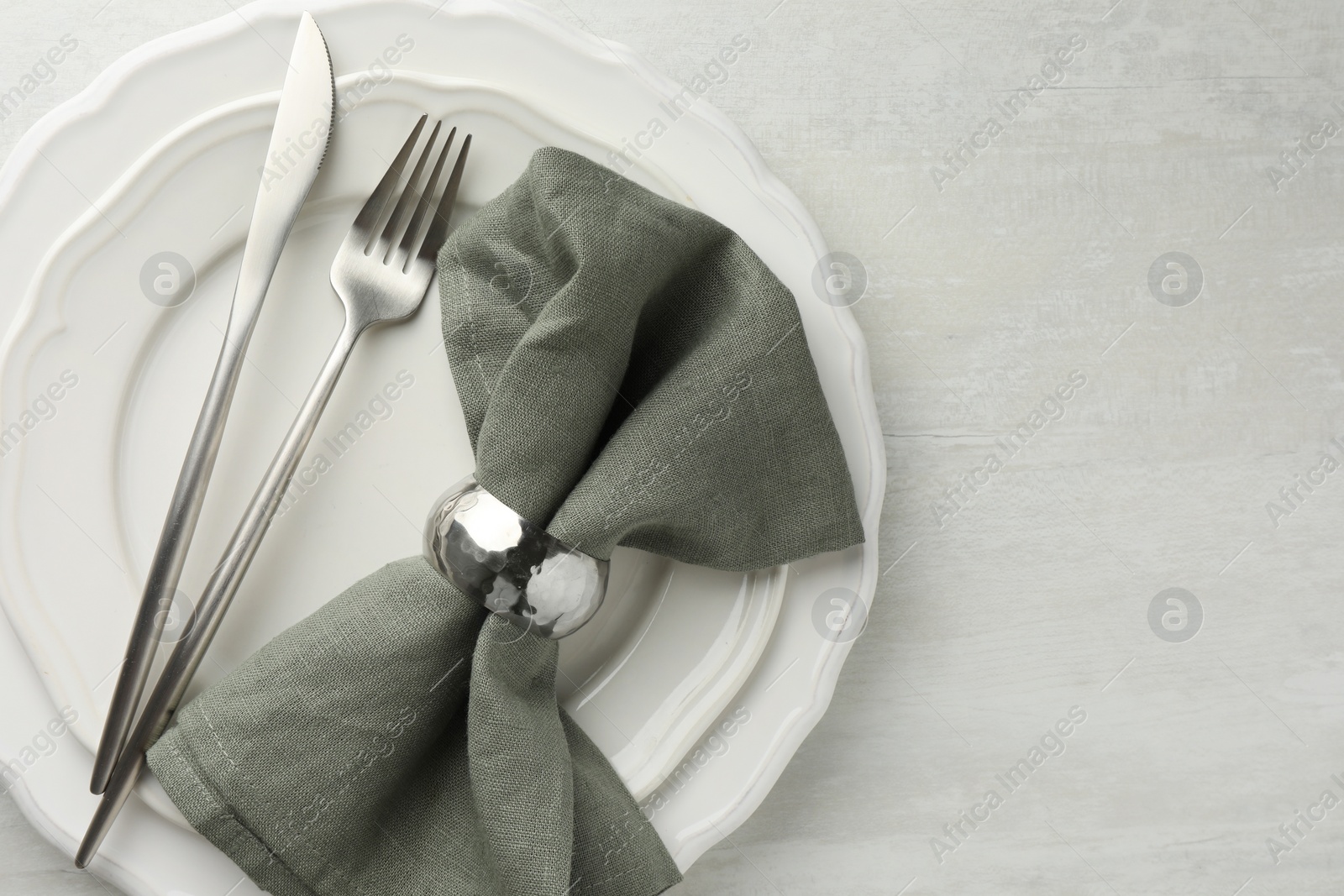 Photo of Stylish setting with cutlery, napkin and plates on light textured table, top view. Space for text