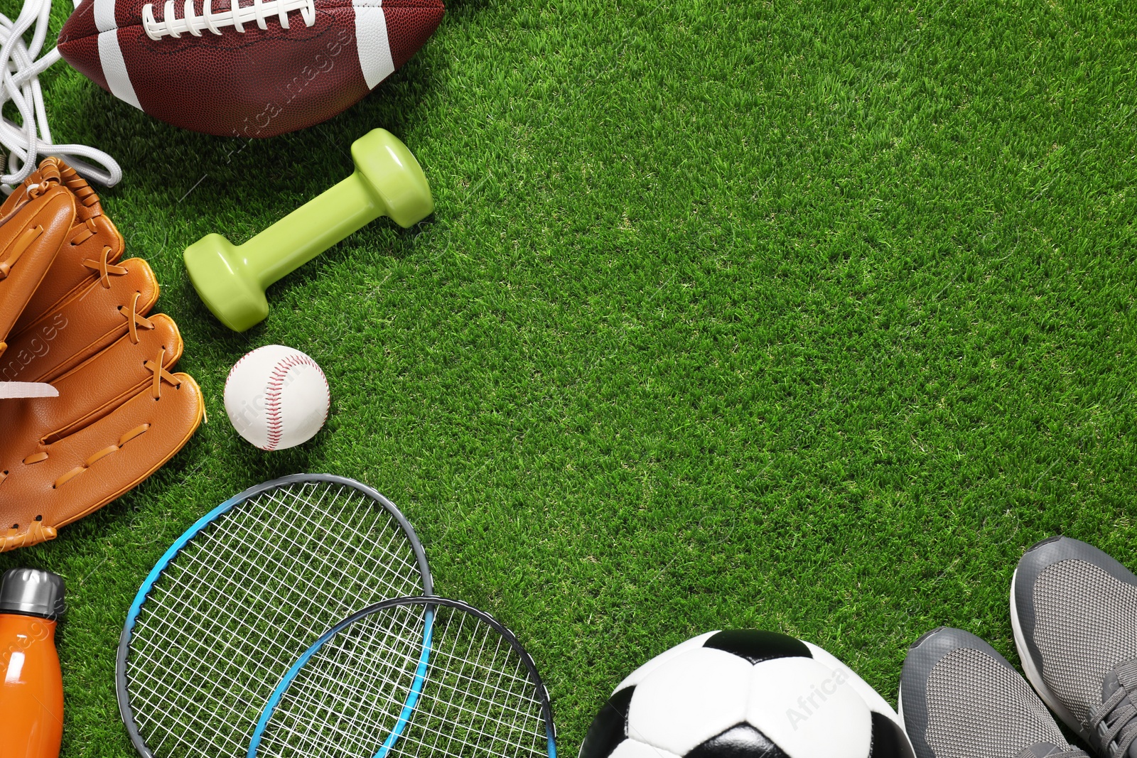 Photo of Different sport tools on green grass, flat lay. Space for text