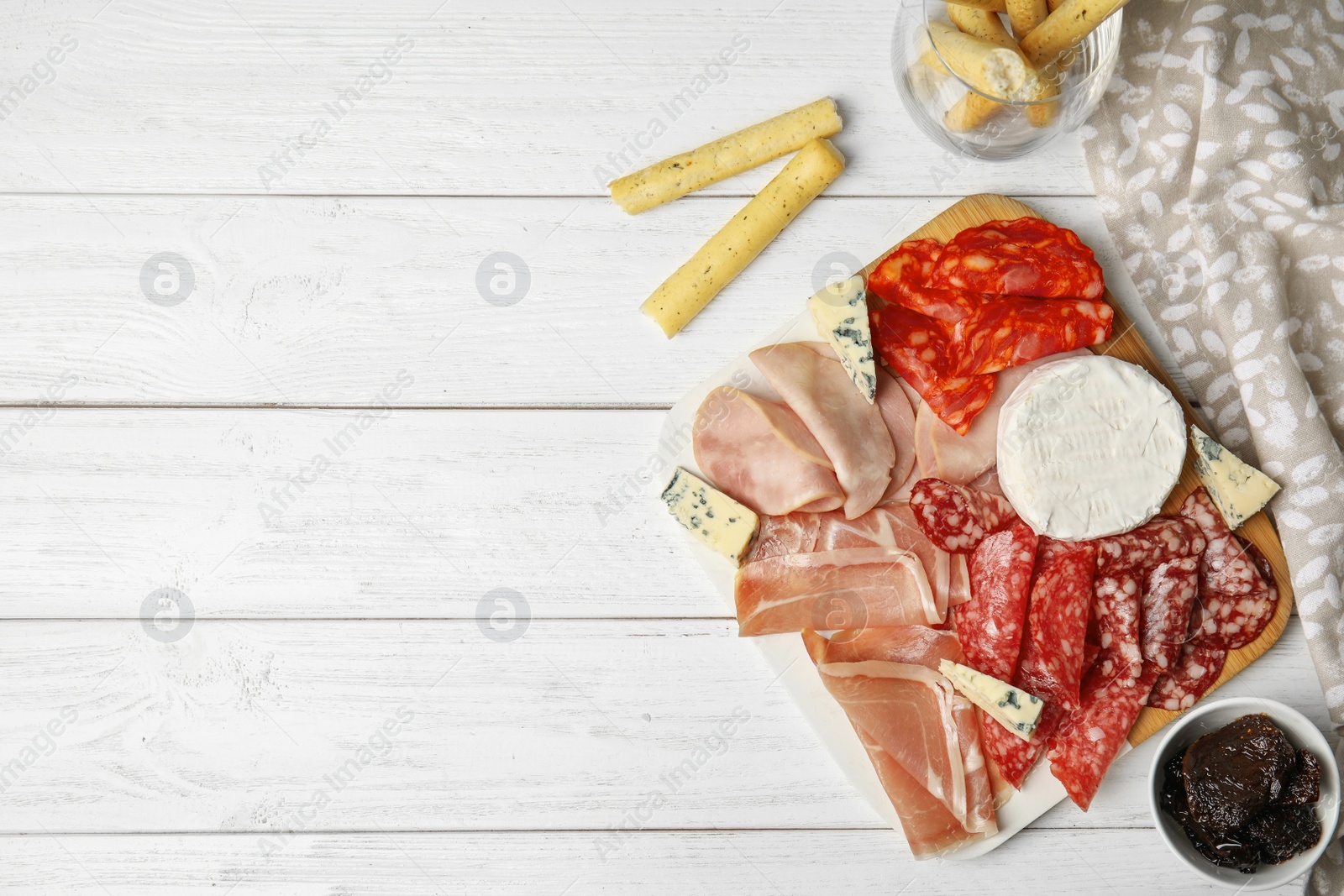 Photo of Tasty ham with other delicacies served on white wooden table, flat lay. Space for text