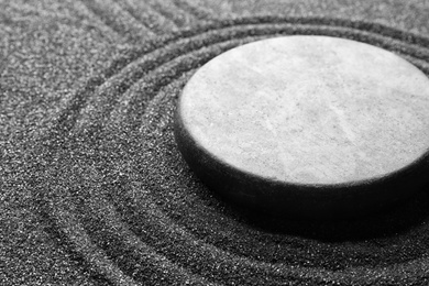 Photo of Zen garden stone on black sand with pattern, closeup