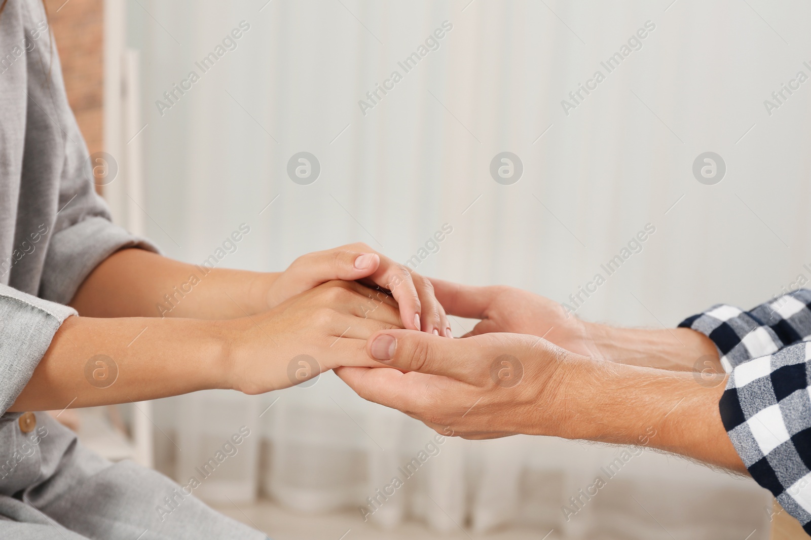 Photo of Man holding woman's hands indoors, closeup. Concept of support and help