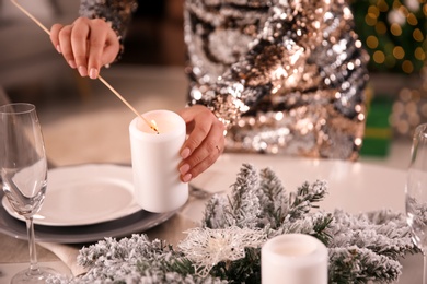 Photo of Young woman setting table for Christmas dinner indoors, closeup