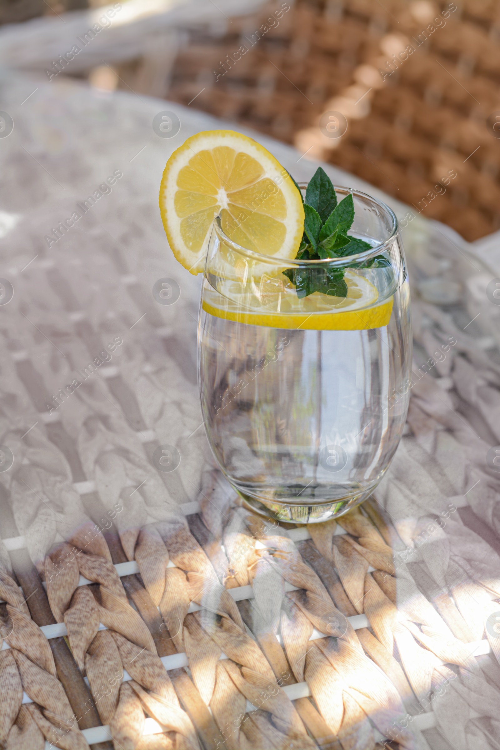 Photo of Refreshing water with lemon and mint on glass table