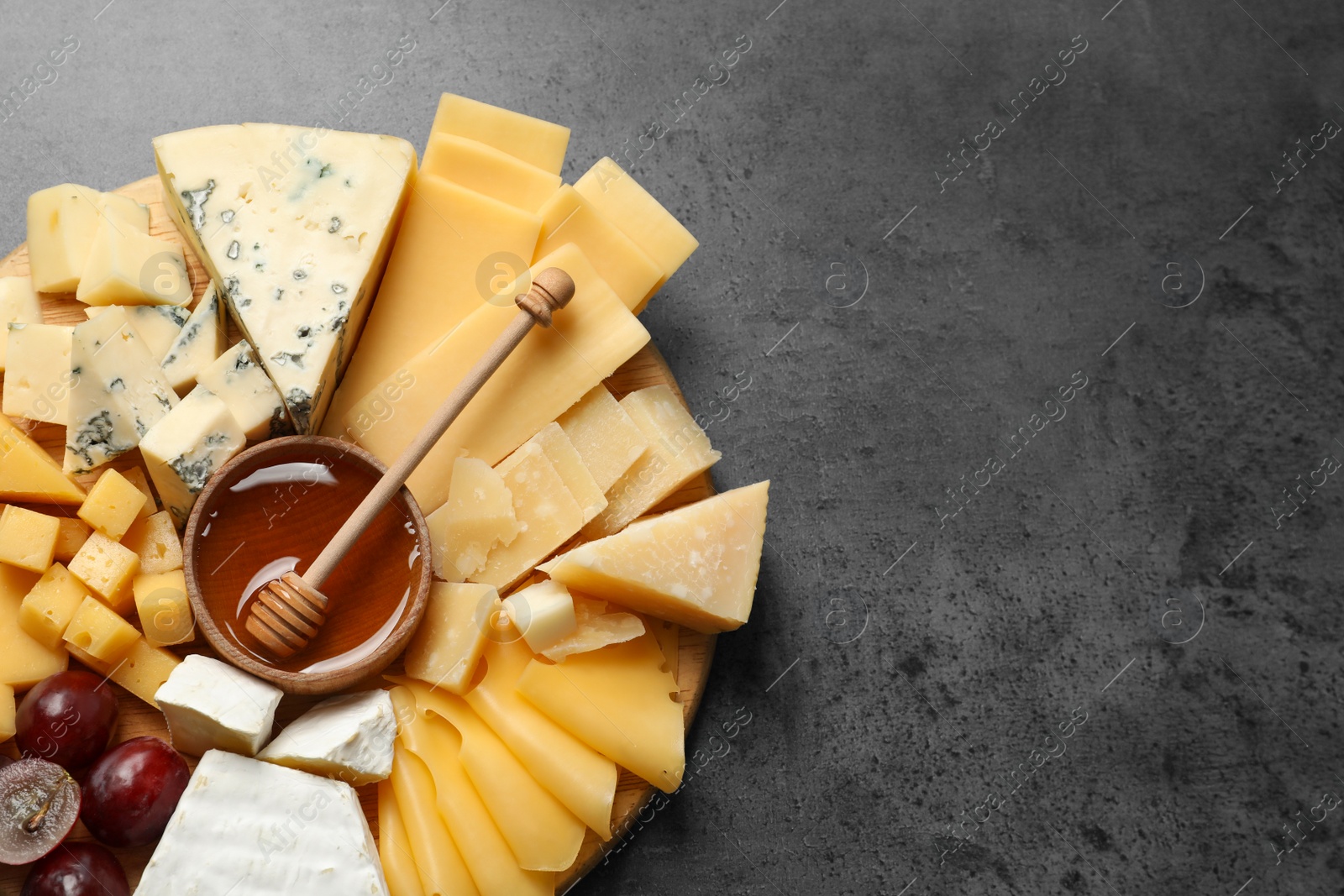 Photo of Different types of delicious cheese and snacks on served grey table, top view. Space for text