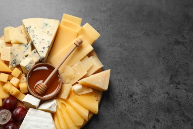 Different types of delicious cheese and snacks on served grey table, top view. Space for text