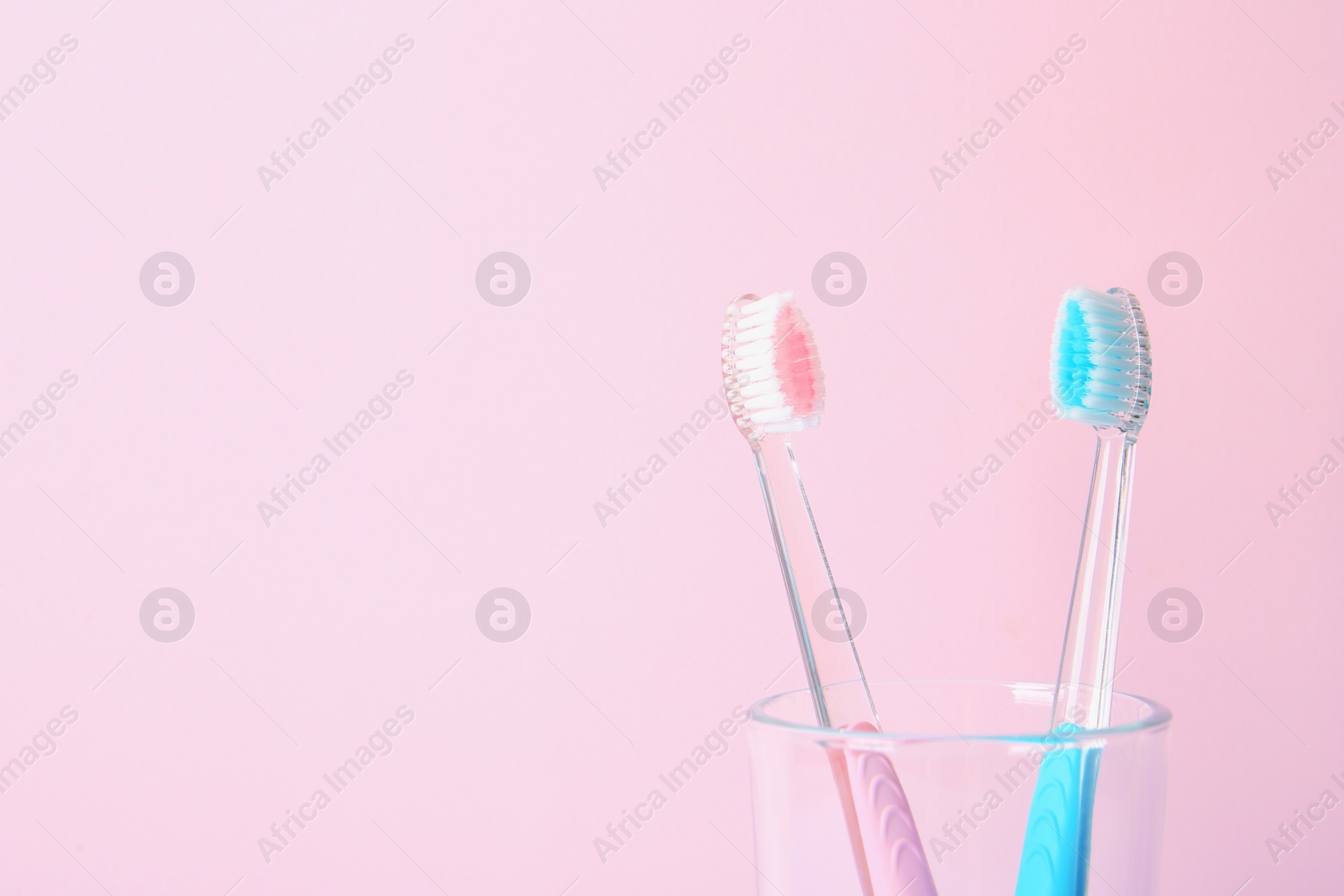 Photo of Cup with toothbrushes against color background