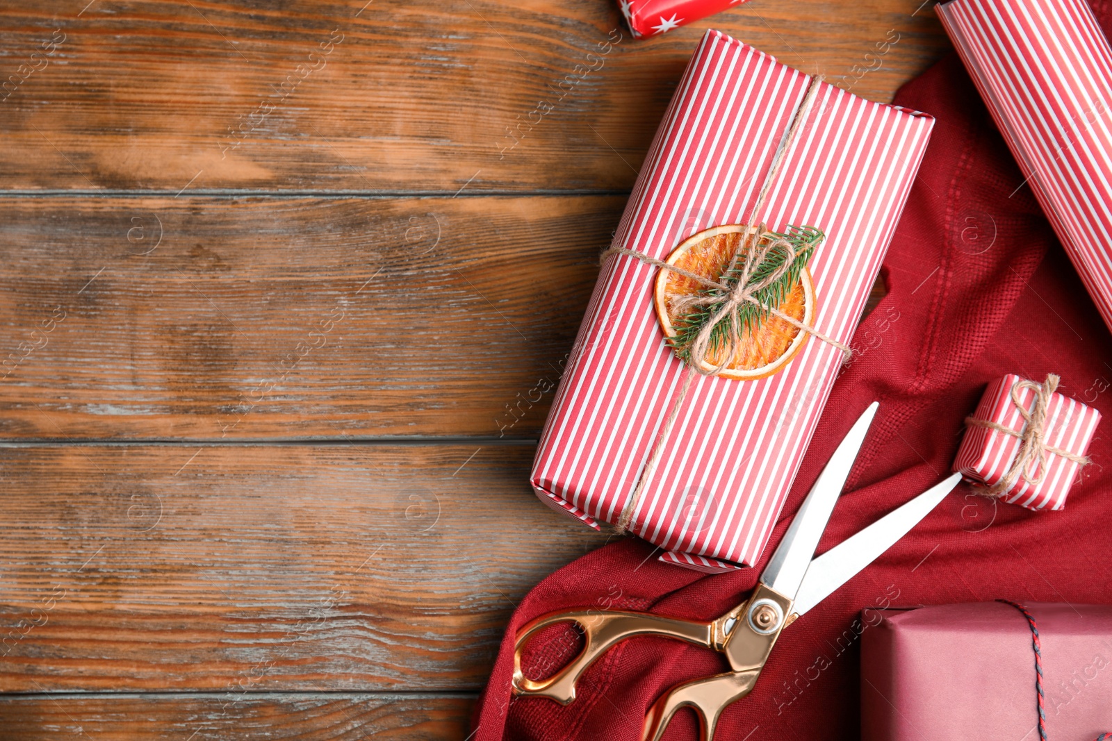 Photo of Flat lay composition of Christmas gift boxes wrapped with color paper on wooden table. Space for text