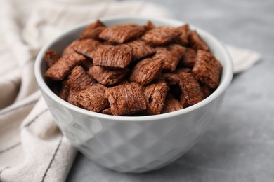 Photo of Chocolate cereal pads in bowl on grey table, closeup