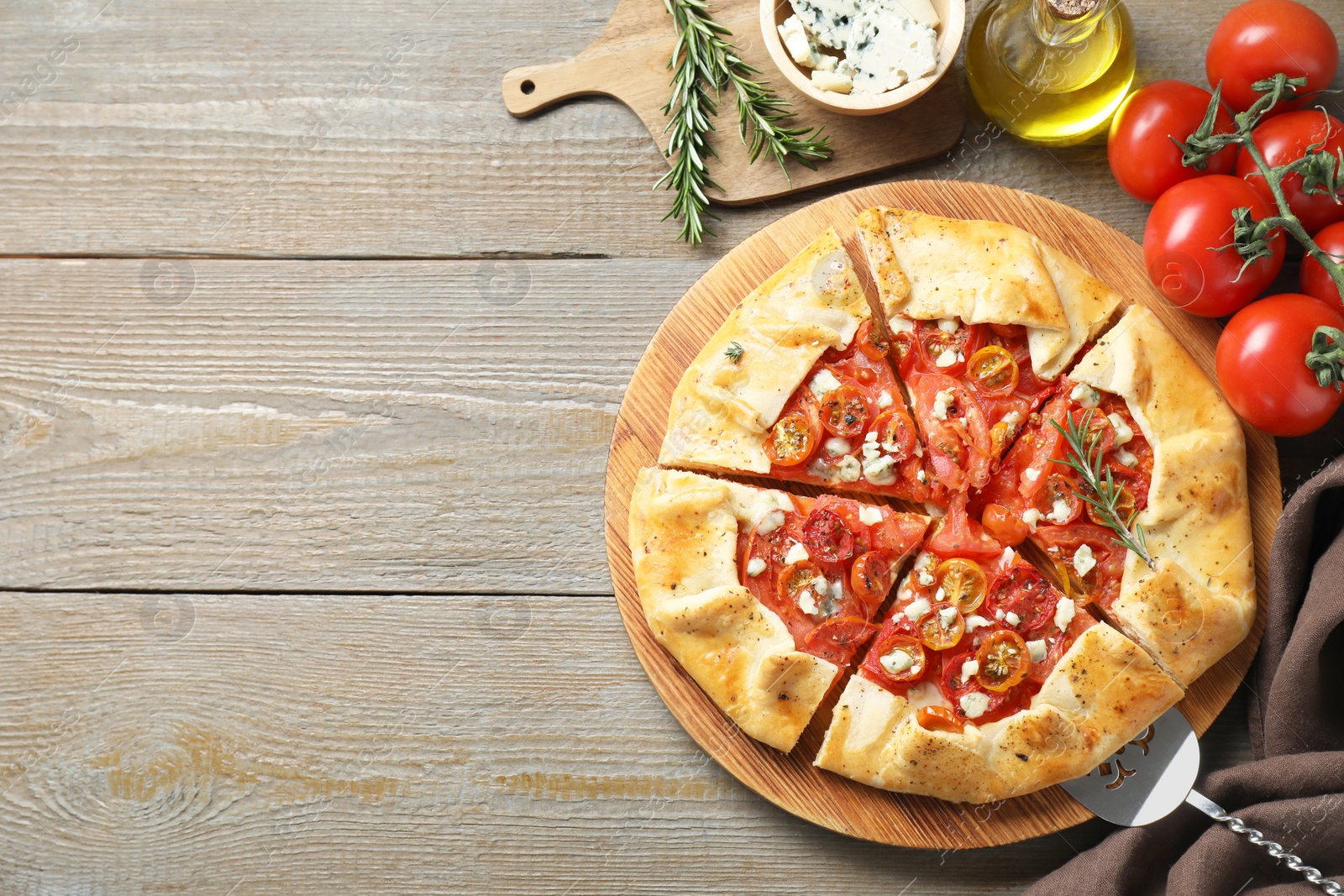 Photo of Flat lay composition of tasty galette with tomato, rosemary and cheese (Caprese galette) on wooden table. Space for text