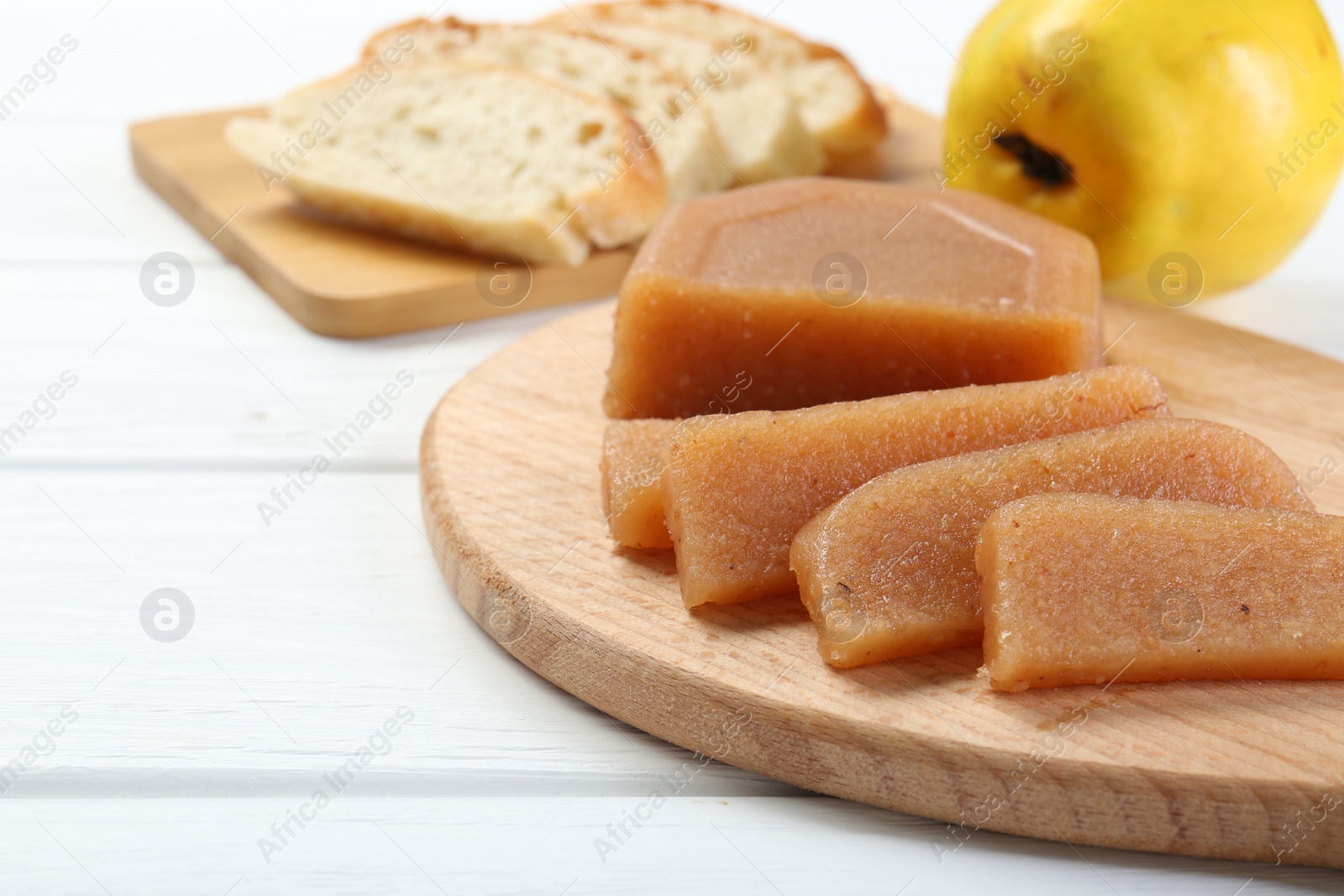 Photo of Tasty sweet quince paste, fresh fruit and bread on white wooden table, closeup