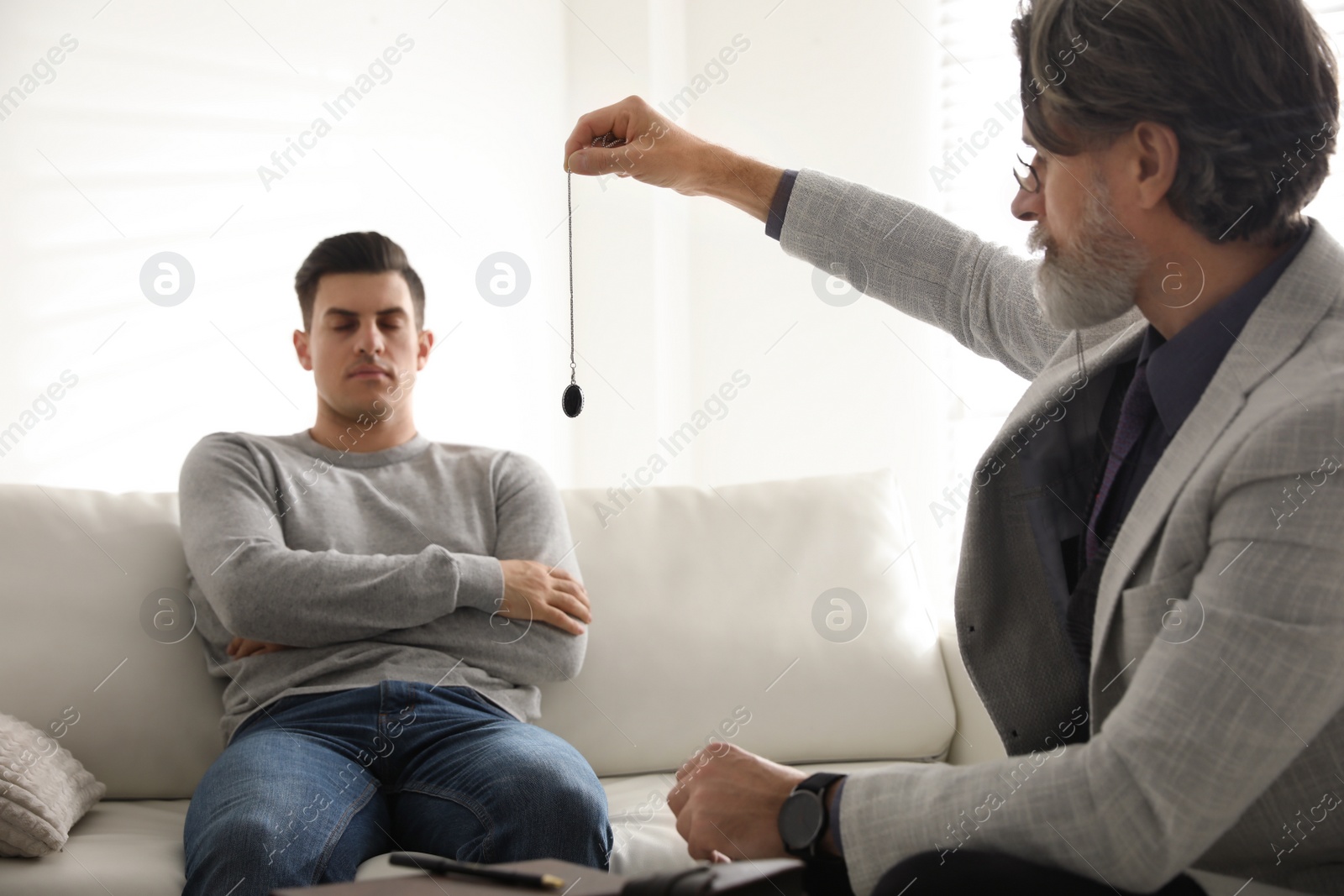 Photo of Psychotherapist using pendulum during hypnotherapy   session in office