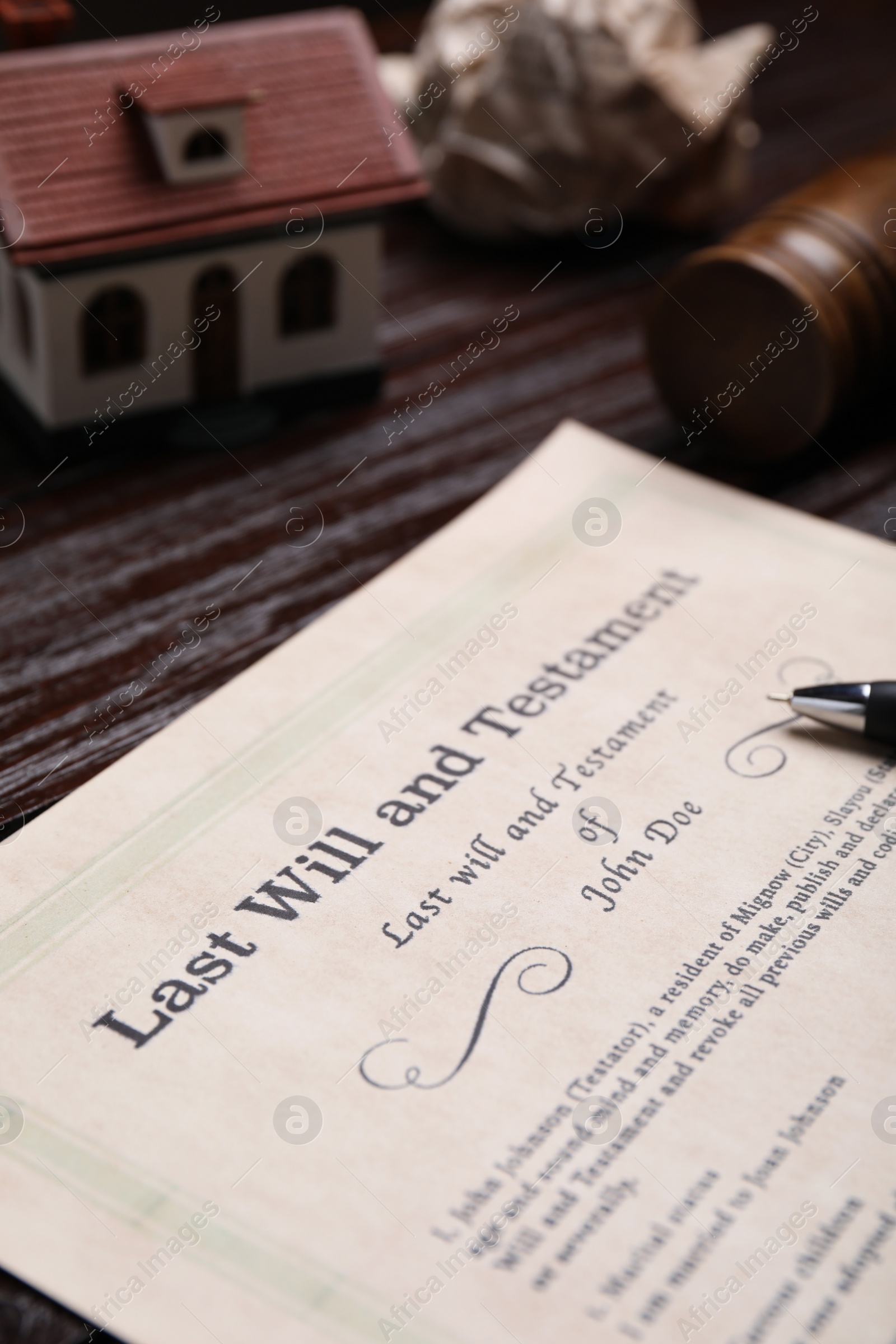 Photo of Last will and testament near house model on wooden table, closeup