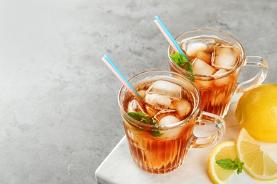 Cups of refreshing iced tea on light table. Space for text