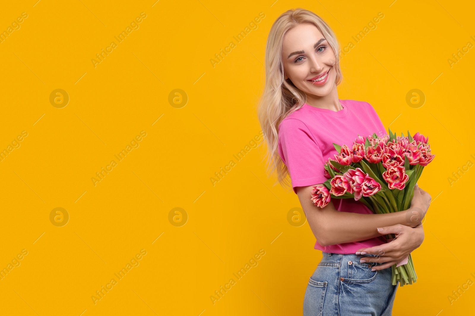 Photo of Happy young woman with beautiful bouquet on orange background. Space for text