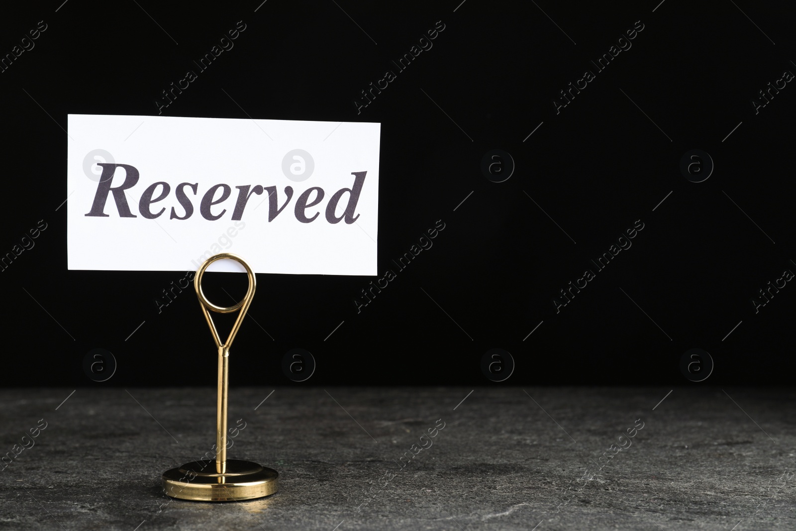 Photo of Elegant sign RESERVED on grey surface, space for text. Table setting element
