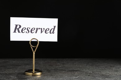 Photo of Elegant sign RESERVED on grey surface, space for text. Table setting element