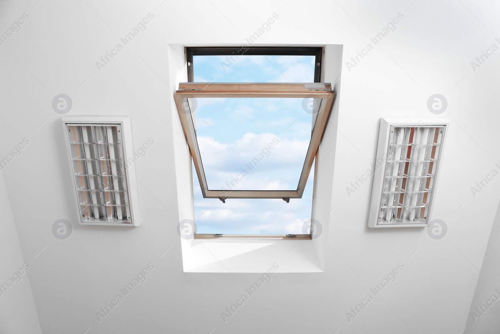 Photo of Open skylight roof window on slanted ceiling in attic room, bottom view