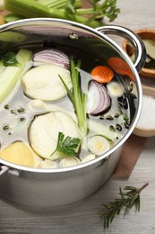 Pot and different ingredients for cooking tasty bouillon on white wooden table