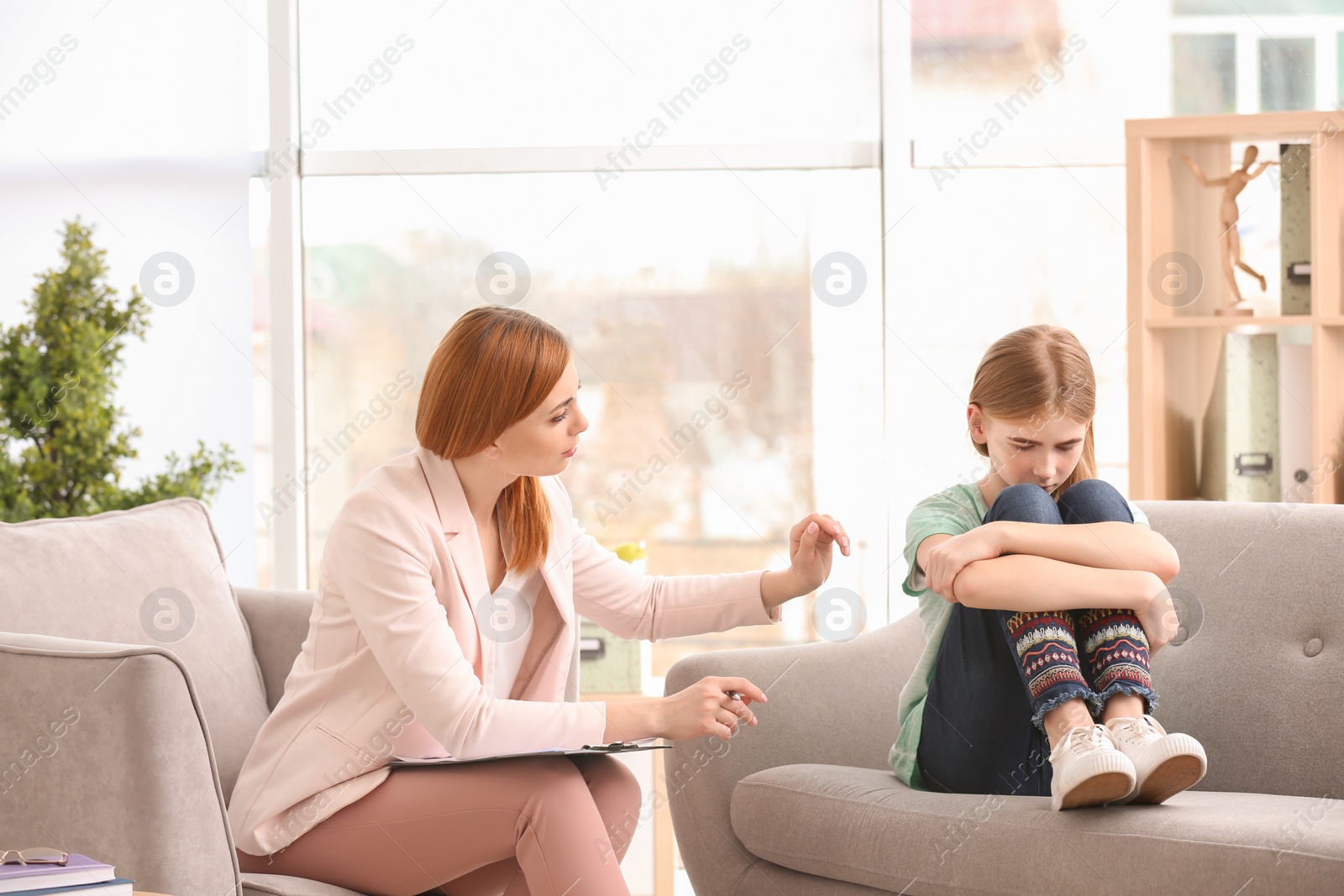 Photo of Young female psychologist working with teenage girl in office