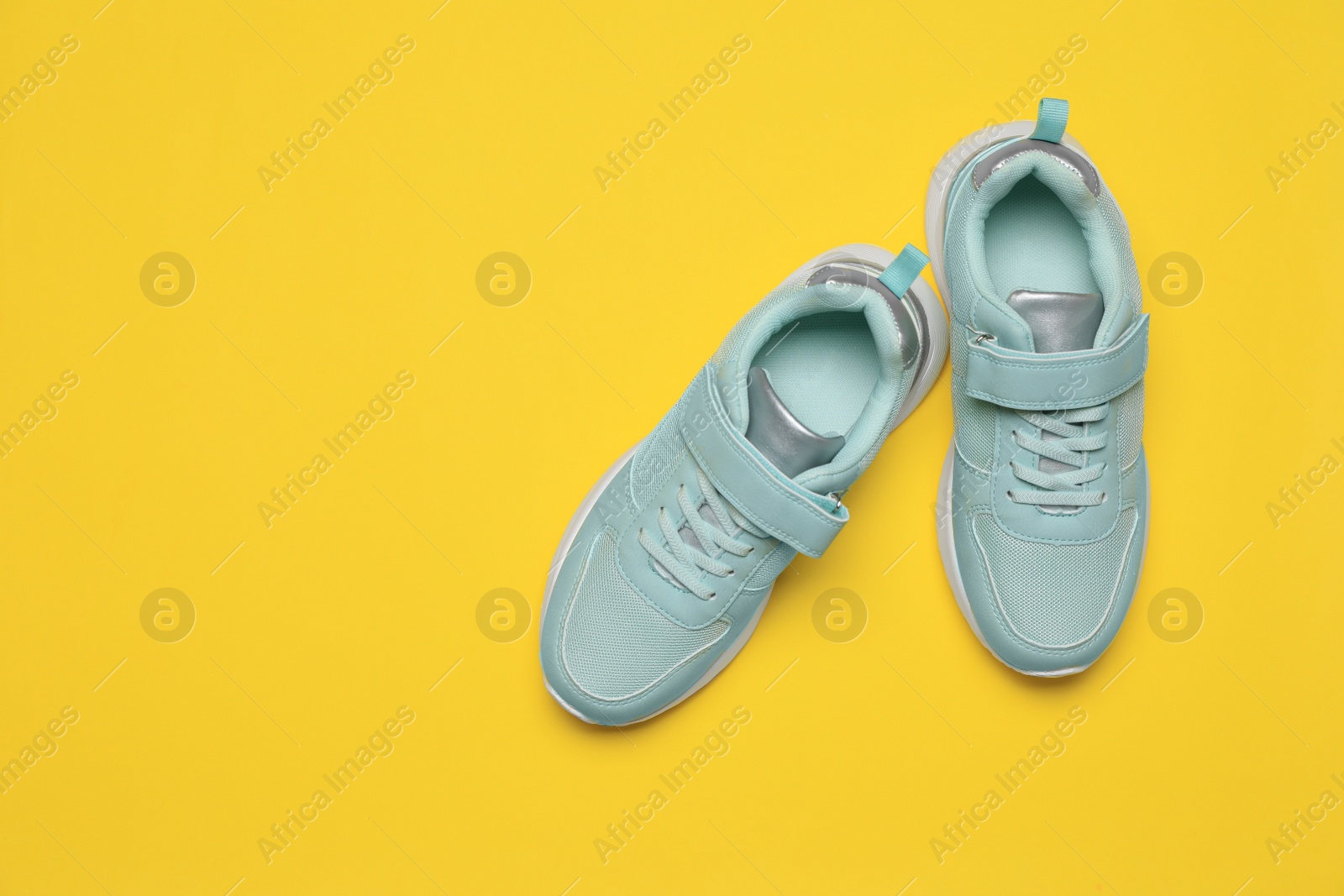 Photo of Pair of comfortable sports shoes on yellow background, flat lay. Space for text