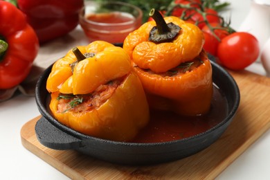 Photo of Tasty stuffed peppers in pan on light table, closeup