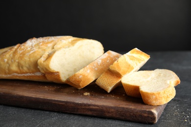 Photo of Board with tasty wheat bread on table