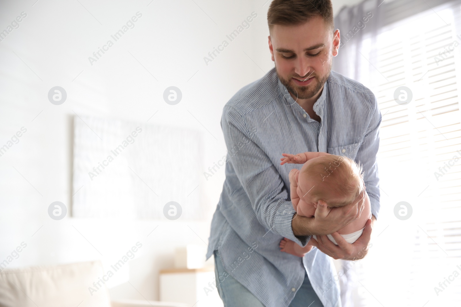 Photo of Father with his newborn son at home. Space for text