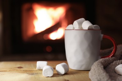 Tasty drink with marshmallows in cup on wooden table, closeup. Space for text