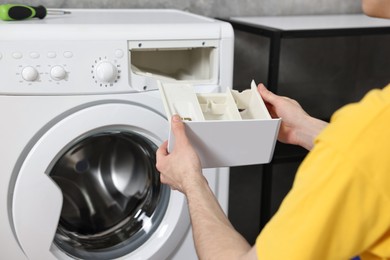 Plumber pulling detergent drawer out of washing machine indoors, closeup